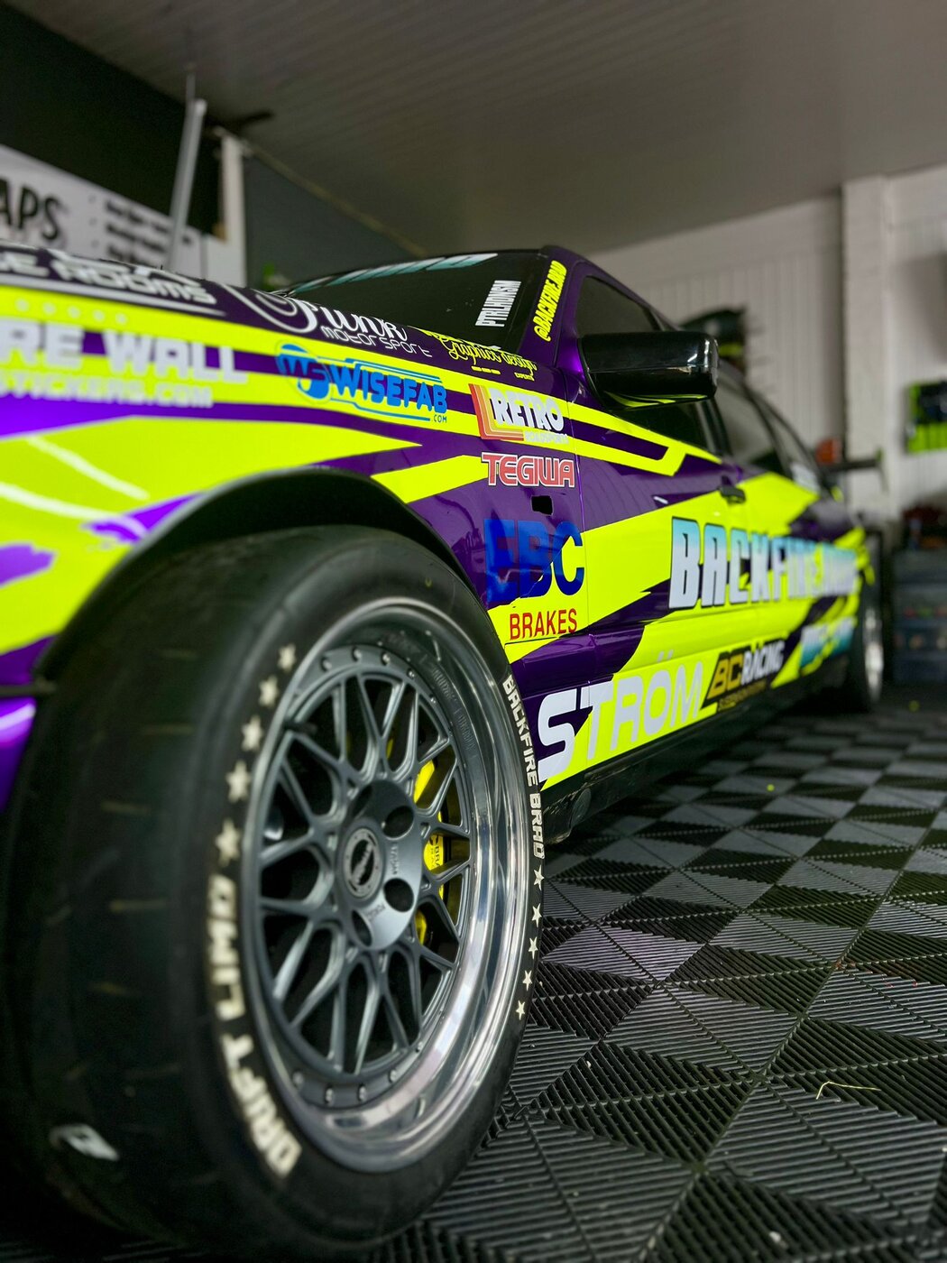 Side profile showing the full custom racing livery with neon yellow graphics on purple