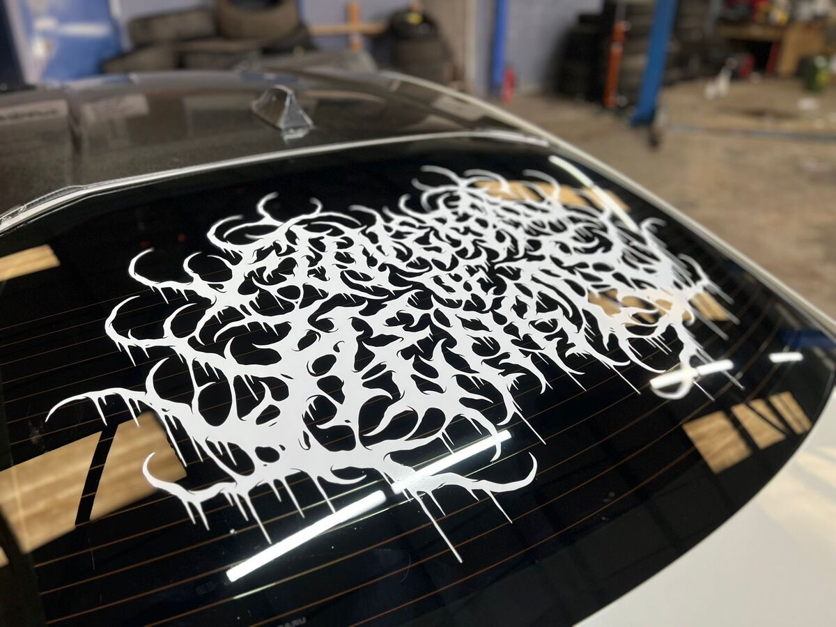 Close-up detail of intricate custom tattoo-style calligraphy vinyl graphics on Subaru BRZ rear window