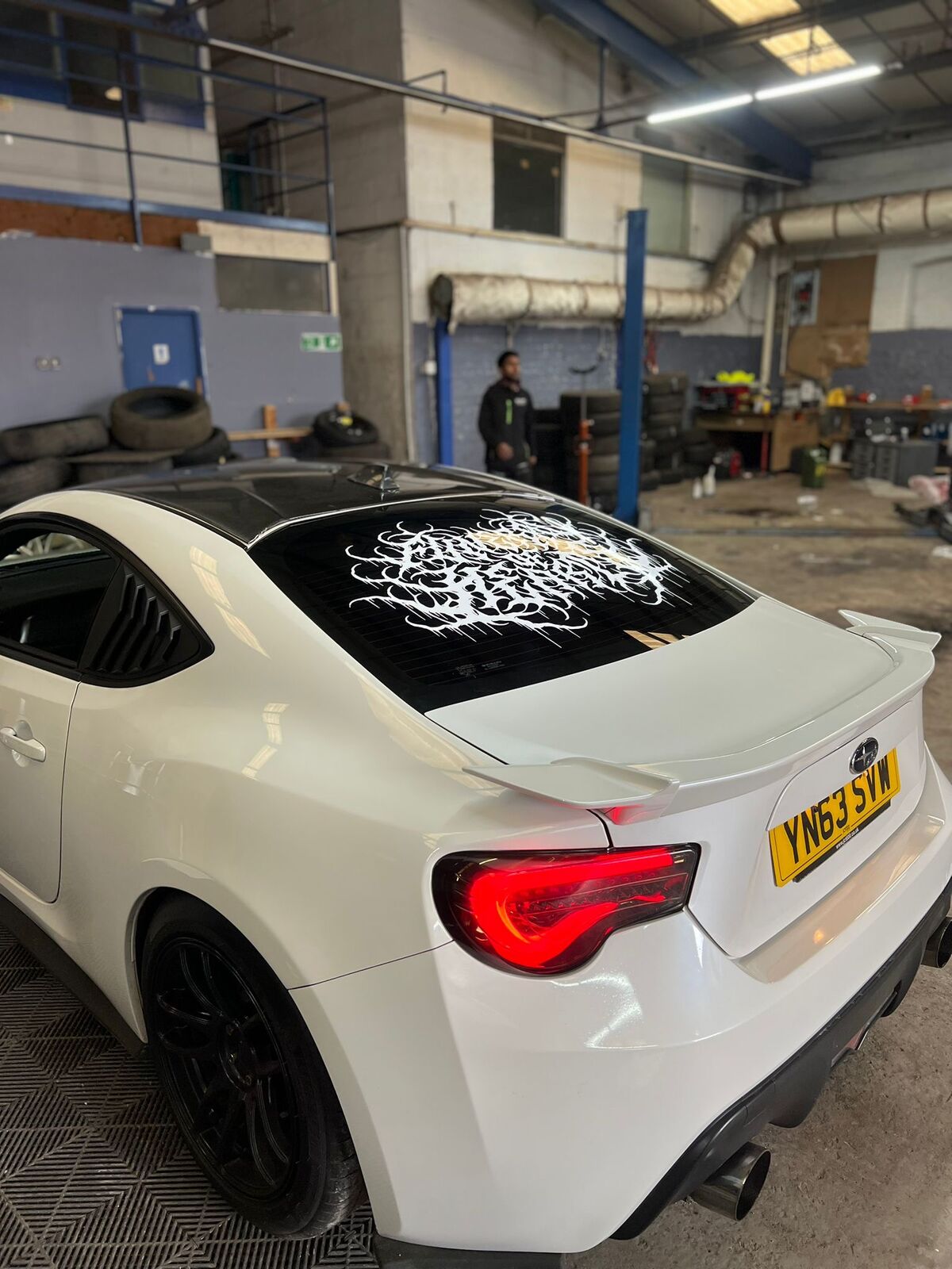 Subaru BRZ in the Wizz's Wraps workshop showing custom tattoo calligraphy vinyl graphics on rear window